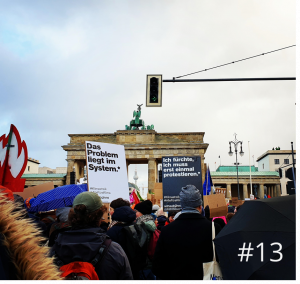 Foto auf dem das Brandenburger Tor zusehen ist, mit Menschen die Plakate zum Thema Klimastreik in die Luft heben