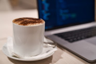 Foto mit einer Tasse Kaffee und daneben steht ein Laptop