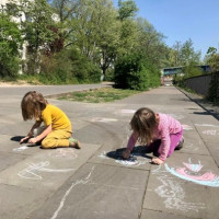Foto von zwei kindern die aus der Straße mit Kreide malen