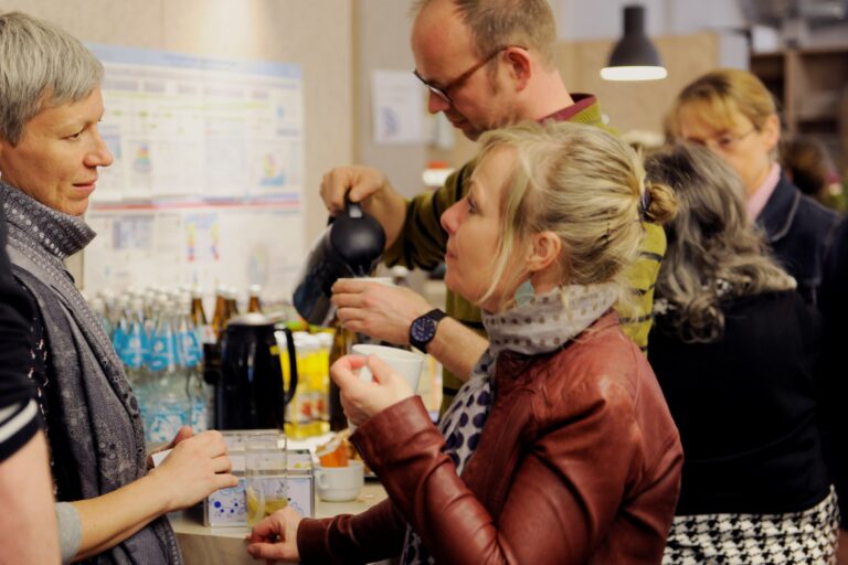 Photo of two people in front of a drinks buffet talking.