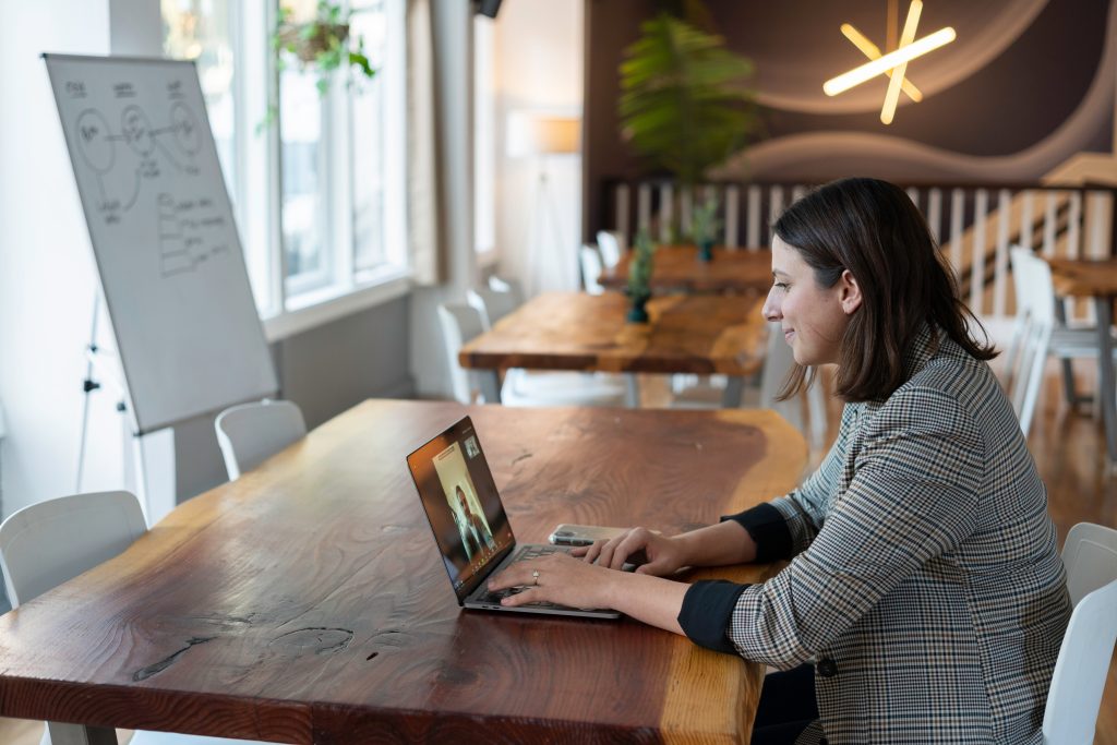 Frau sitzt am Schreibtisch mit Laptop während Sie einen digitalen Meeting führt.
