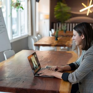 Frau sitzt am Schreibtisch mit Laptop während Sie einen digitalen Meeting hat.